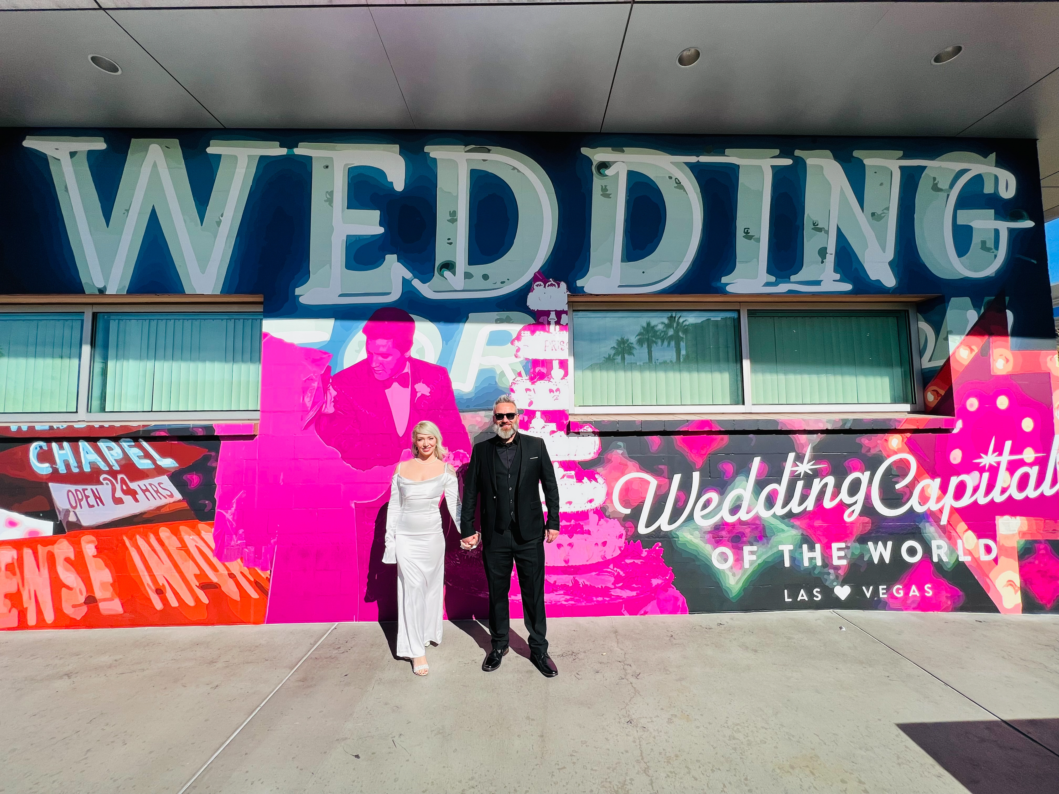 Bride and Groom stand in front of a Wedding mural in Las Vegas (Wedding Capital of the World)