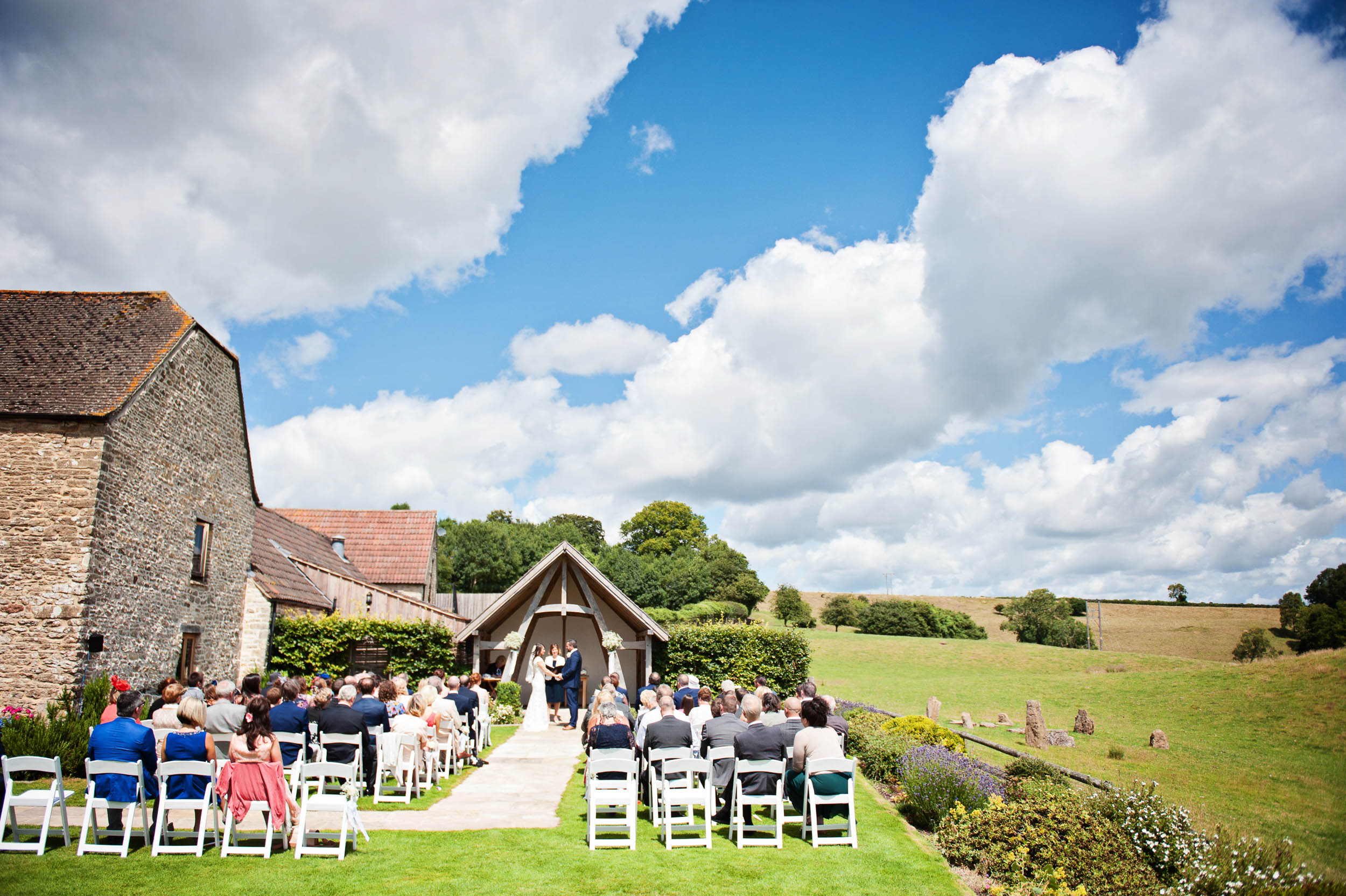 A Bride and Groom say their vow's outside, at the Cotswold Wedding Venue, The Kingscote Barn.