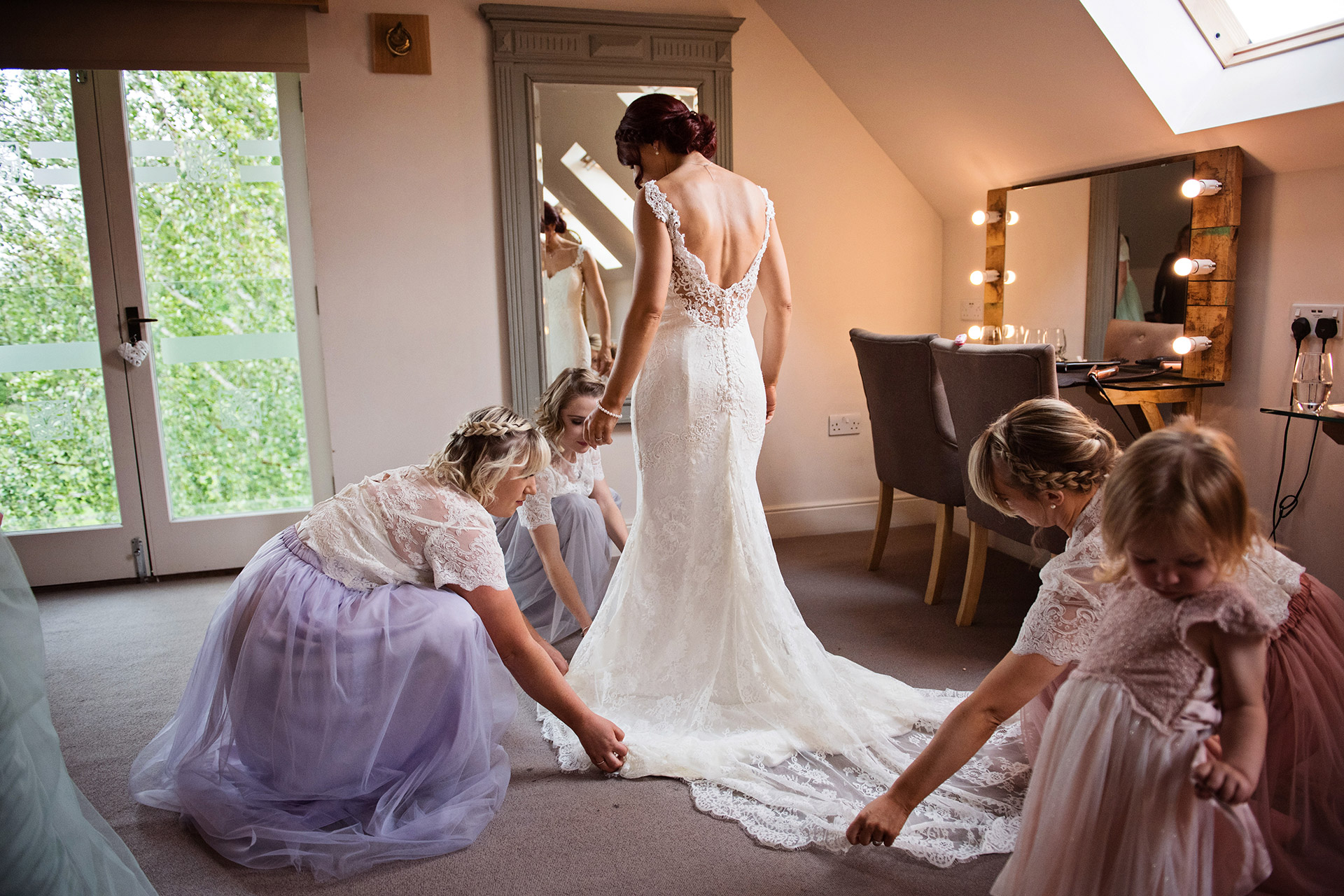 bridesmaids help lay brides wedding dress out