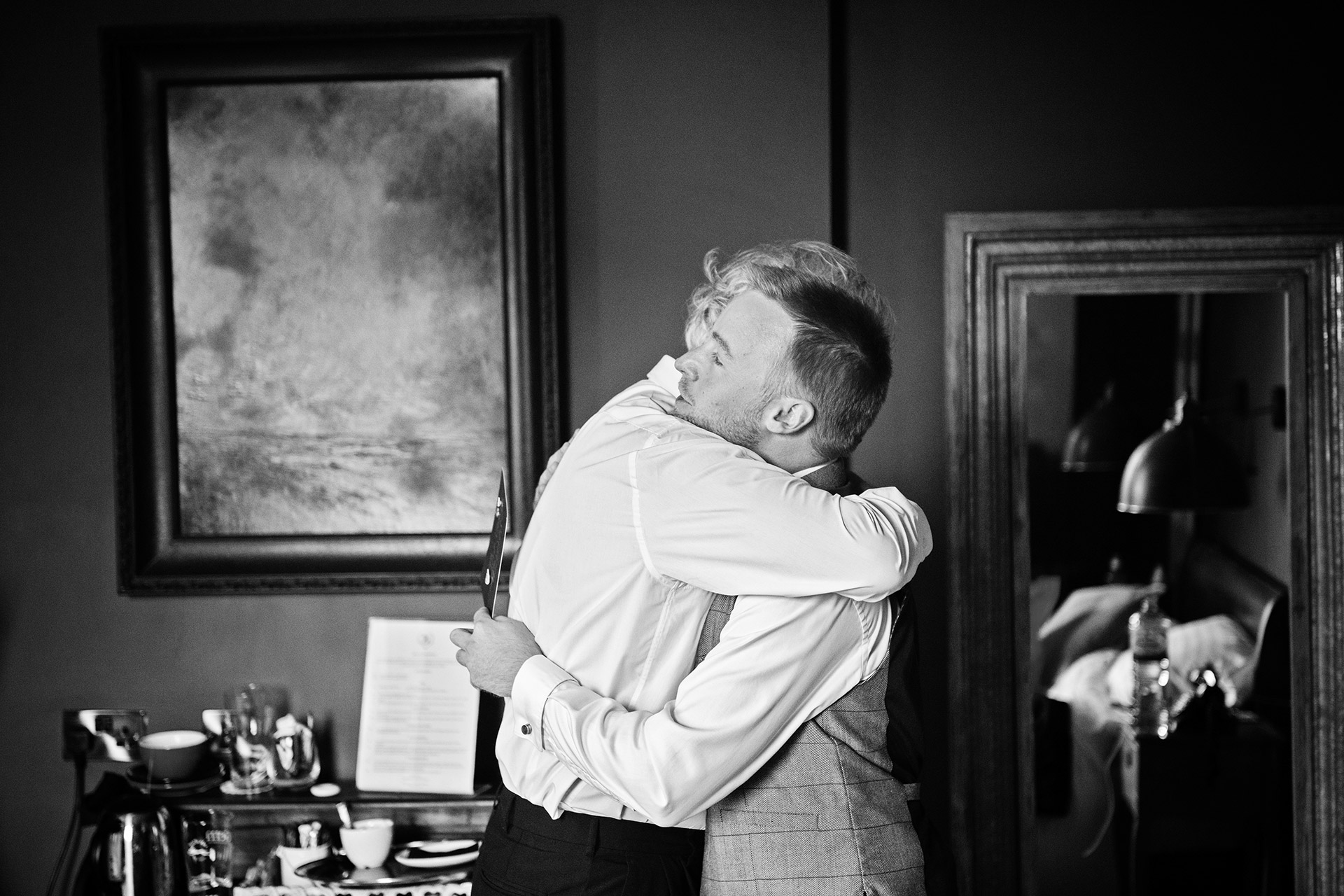 father of groom gives his son, the groom a big hug. 