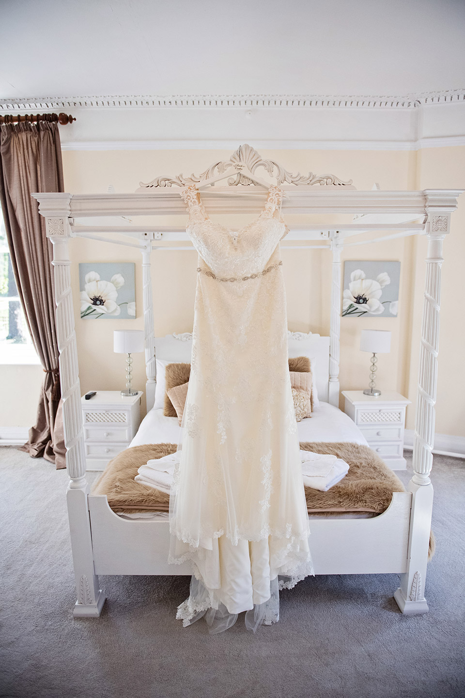 wedding dress hung up on a four poster bed