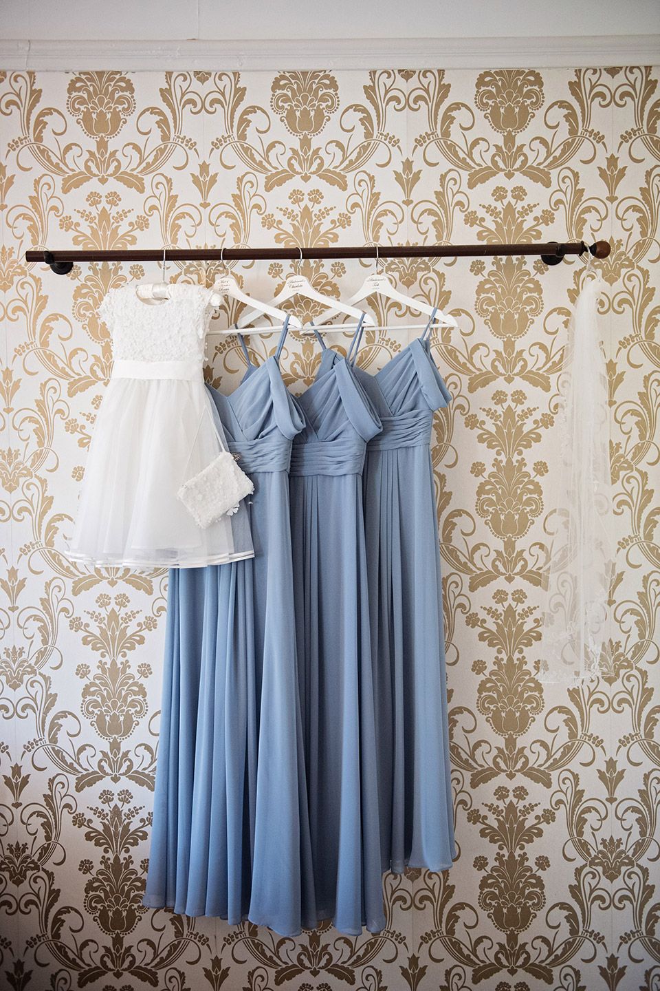 flower girls dress and bridesmaid dresses and veil hang up ready to be worn 