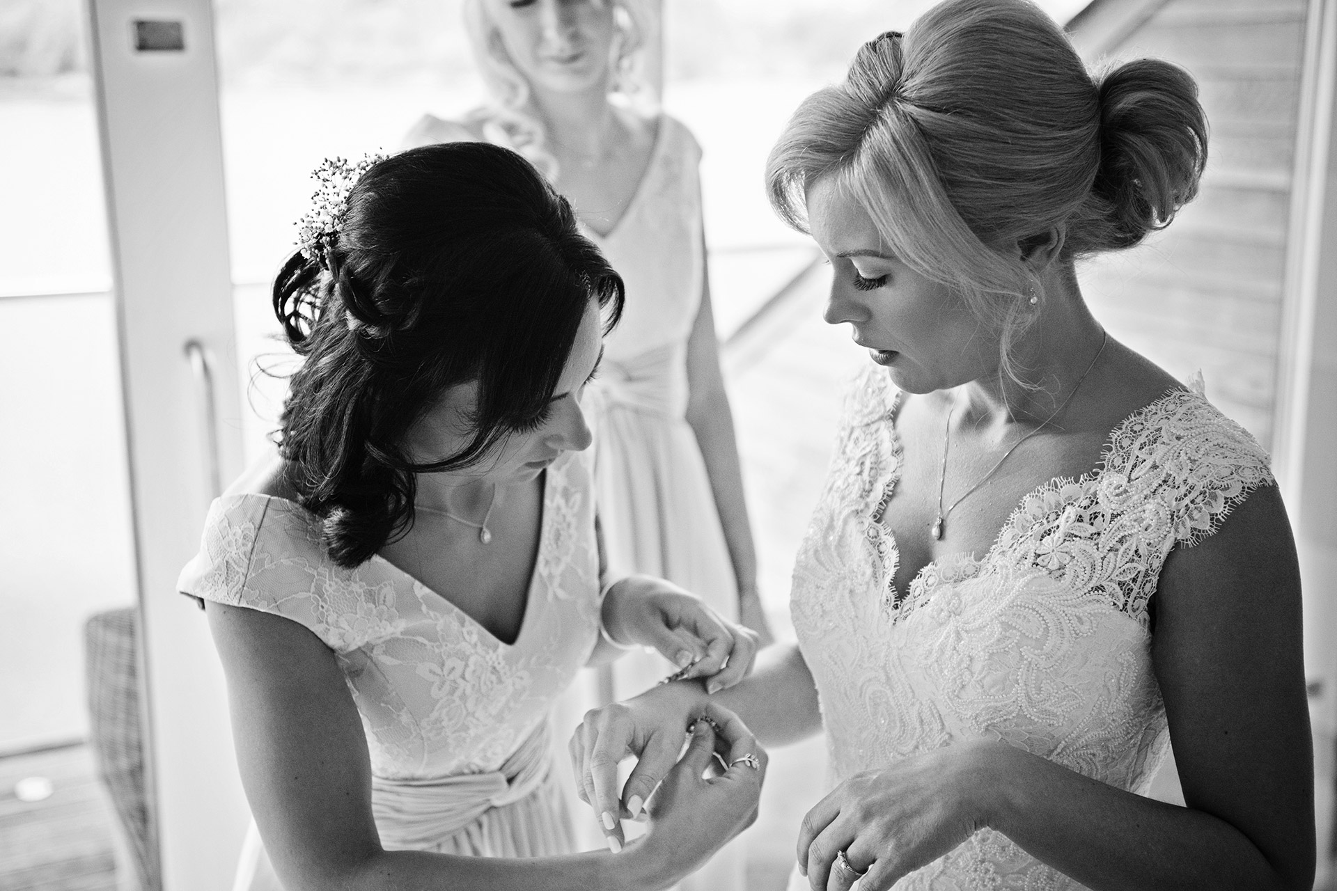 bridesmaid putting a wedding bracelet onto the brides wrist