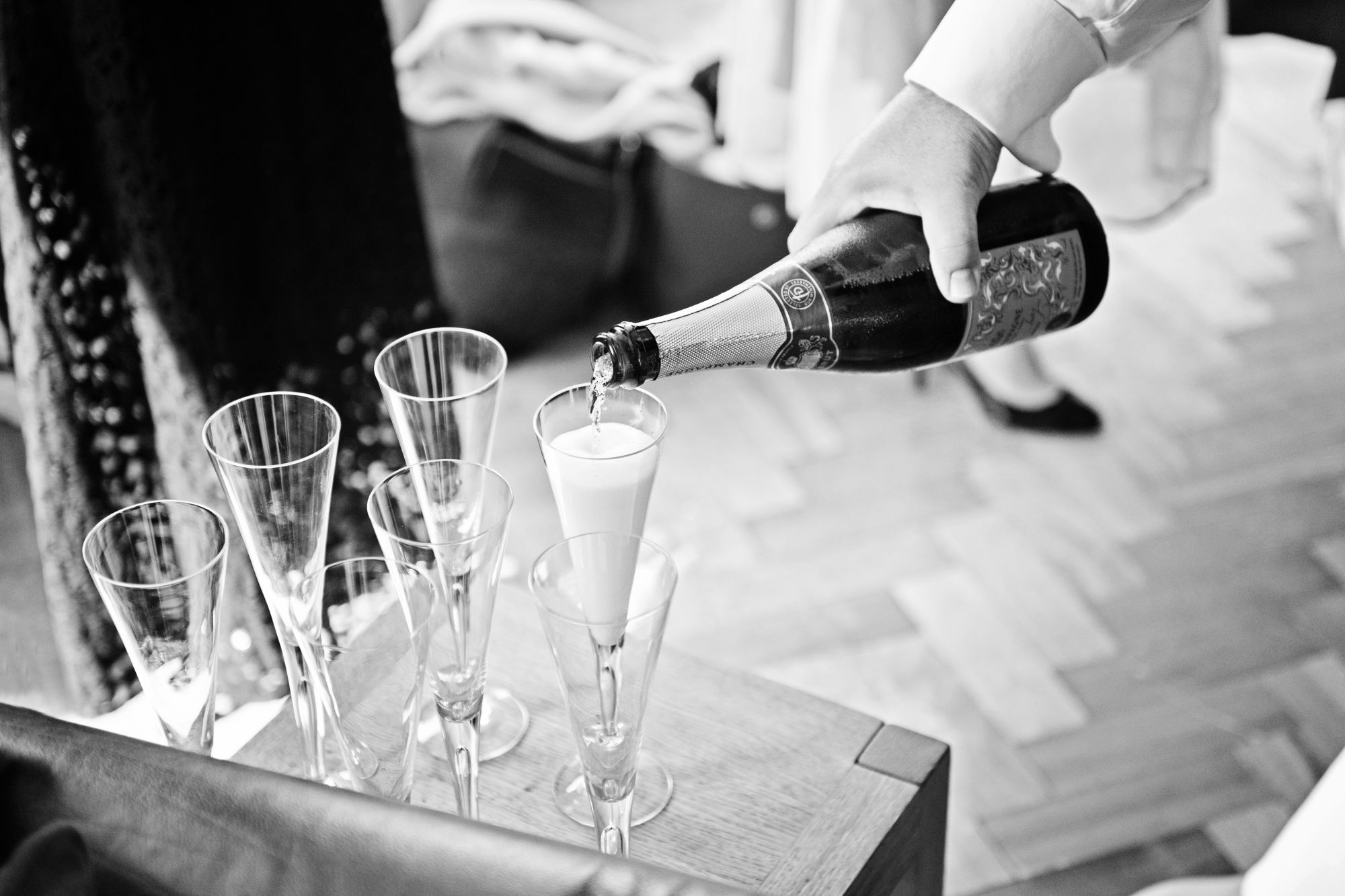 b&w photo of champagne being pored into 6 flutes