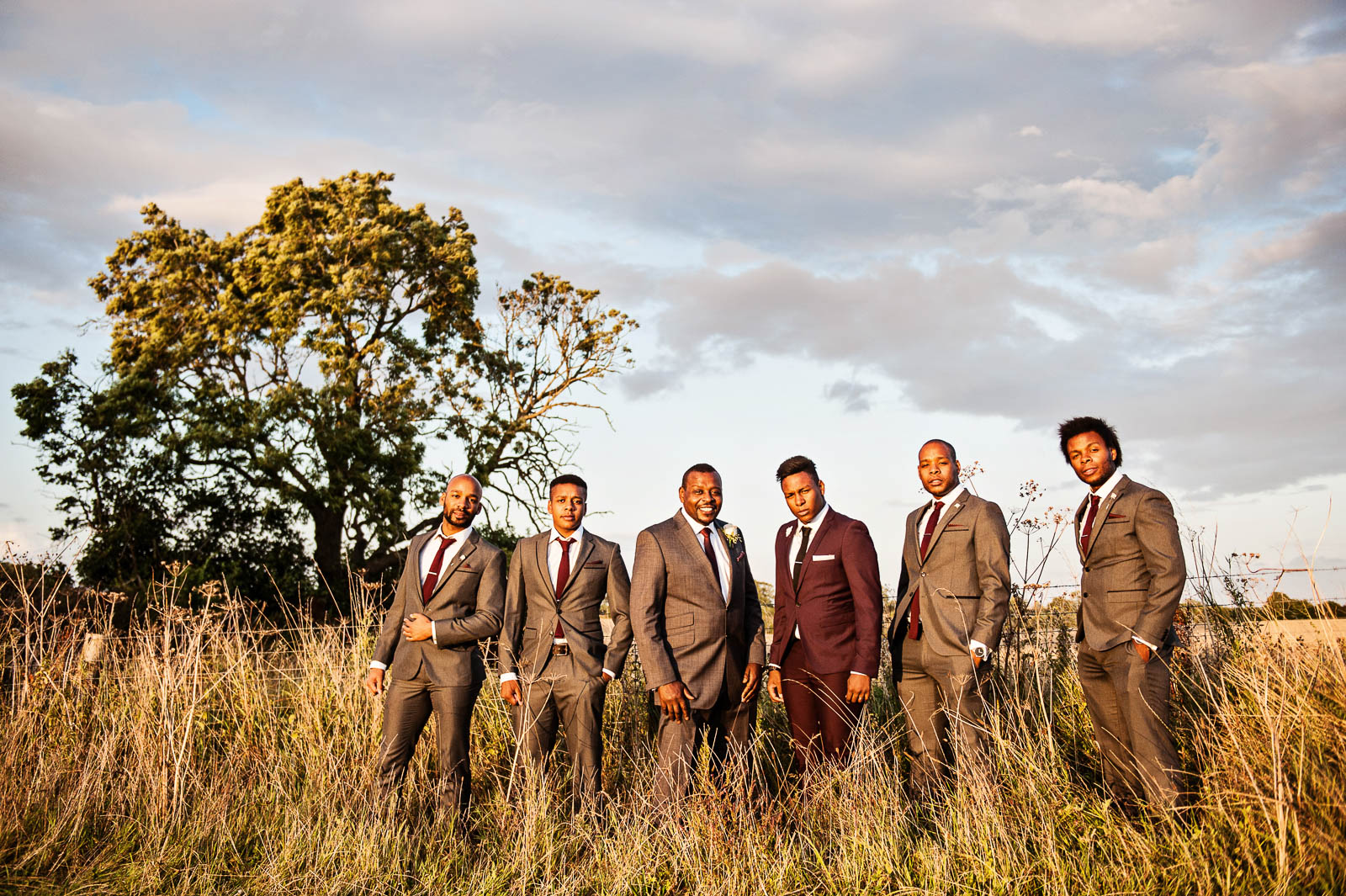 Groomsmen standing in a field with the golden sun shinning on them. 