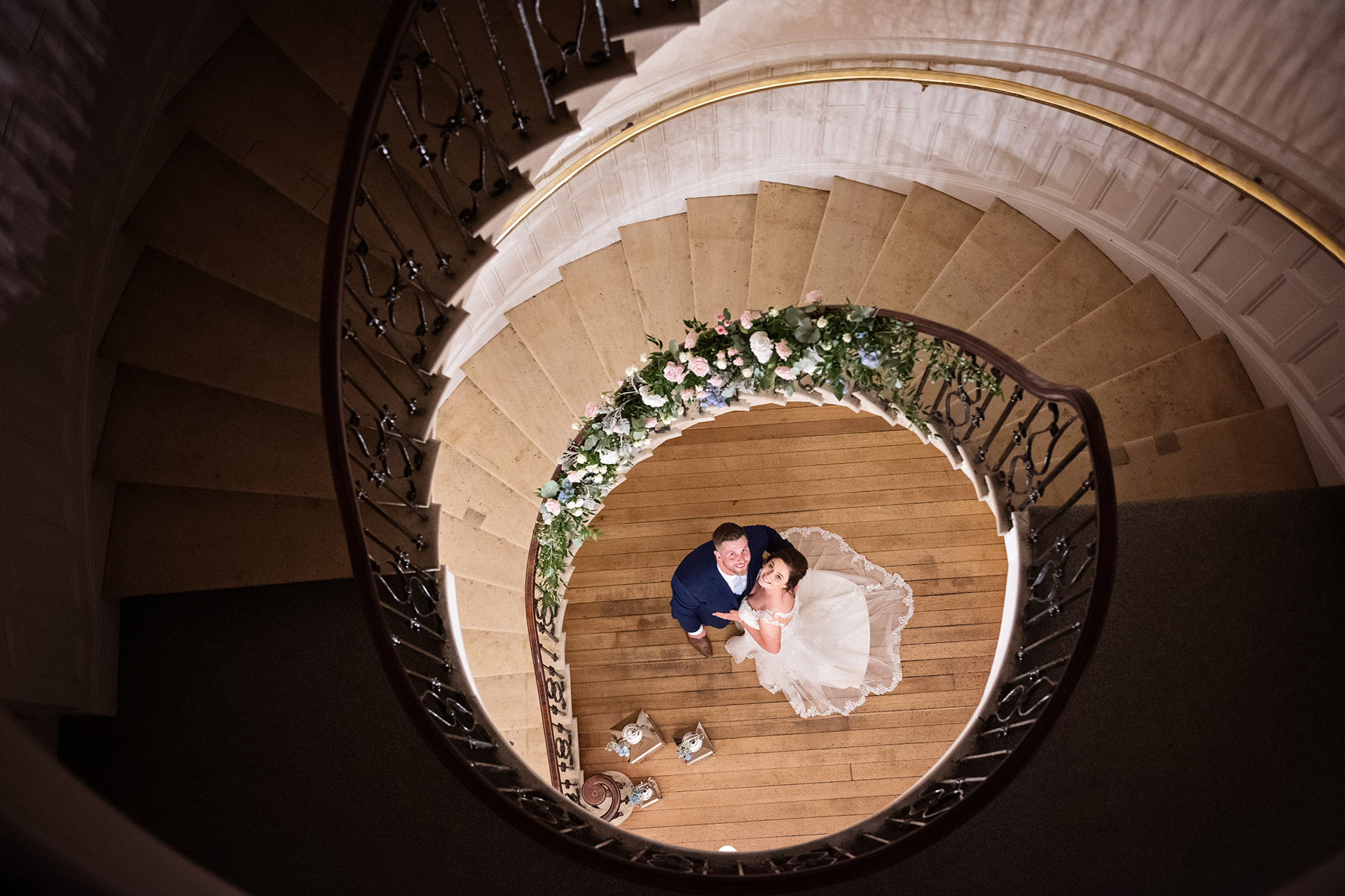 wedding couple look up through a spiral staircase