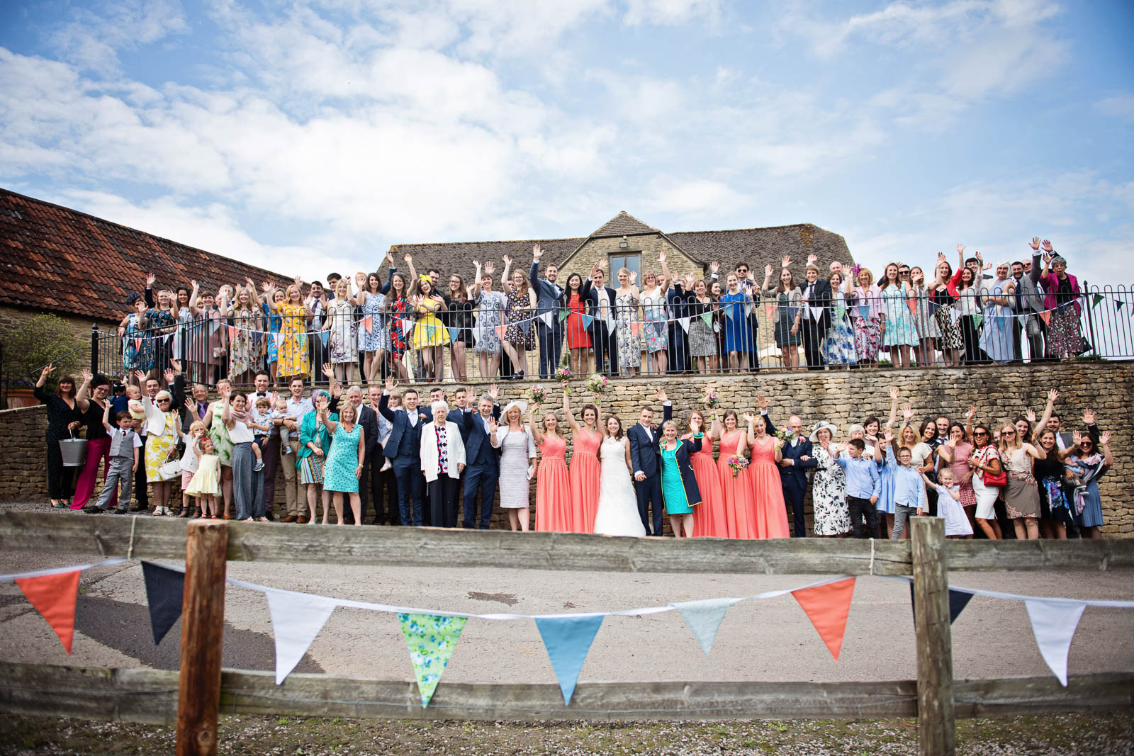 A wedding group shot, with everyone smiling and cheering and their hands in the air like they don't care!