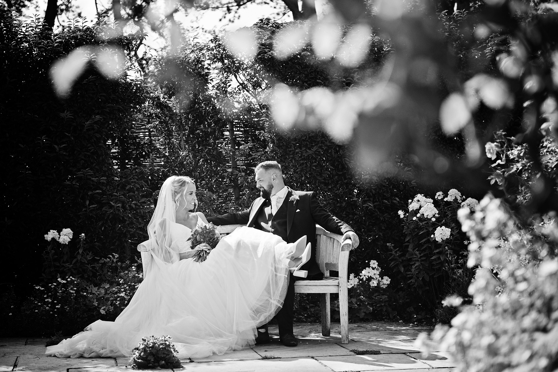 B & W photograph of Bride and Groom sitting on a bench together, taking time out on their wedding day. Taken at The Kingscote Barn.  