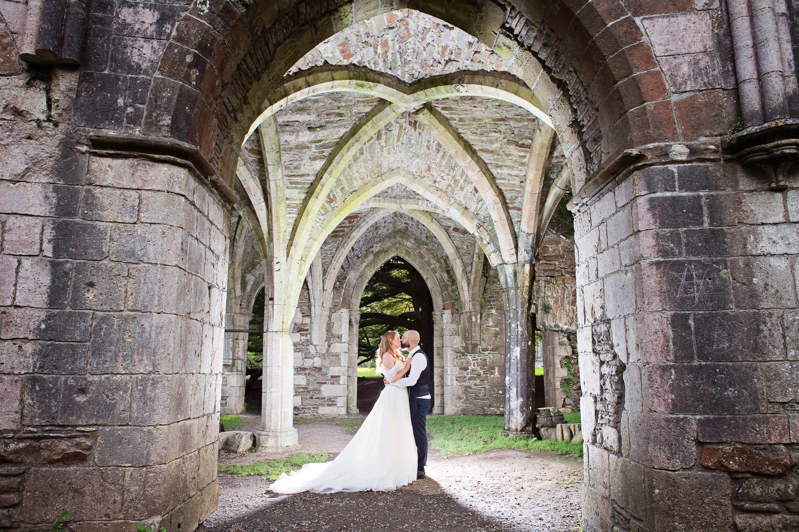 Bride & Groom kiss in archway of Magram Country Park