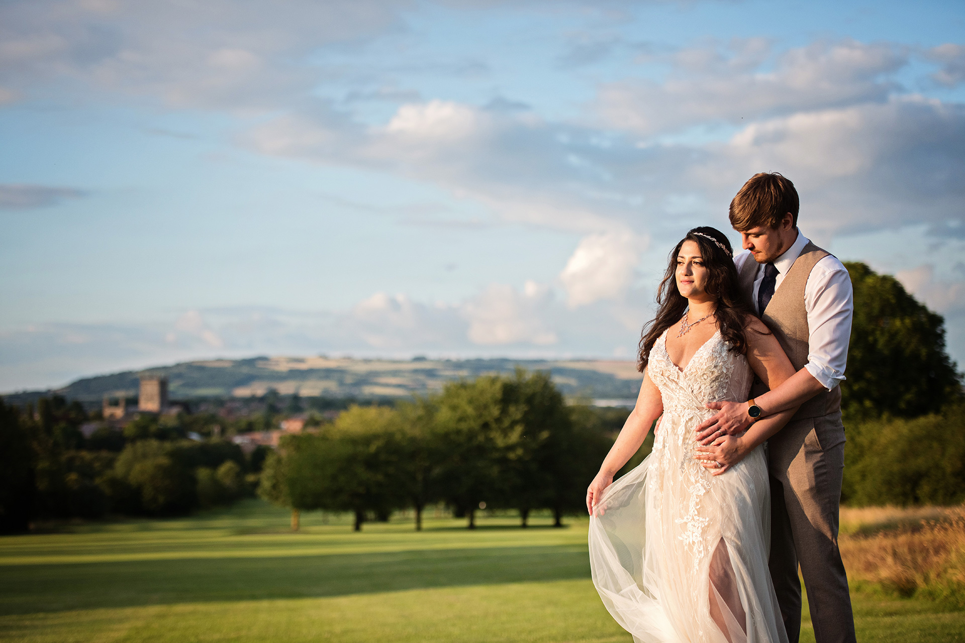 Bride and Groom have a moment during gorgeous golden hour with Tewkesbury Abbey and countryside behind them