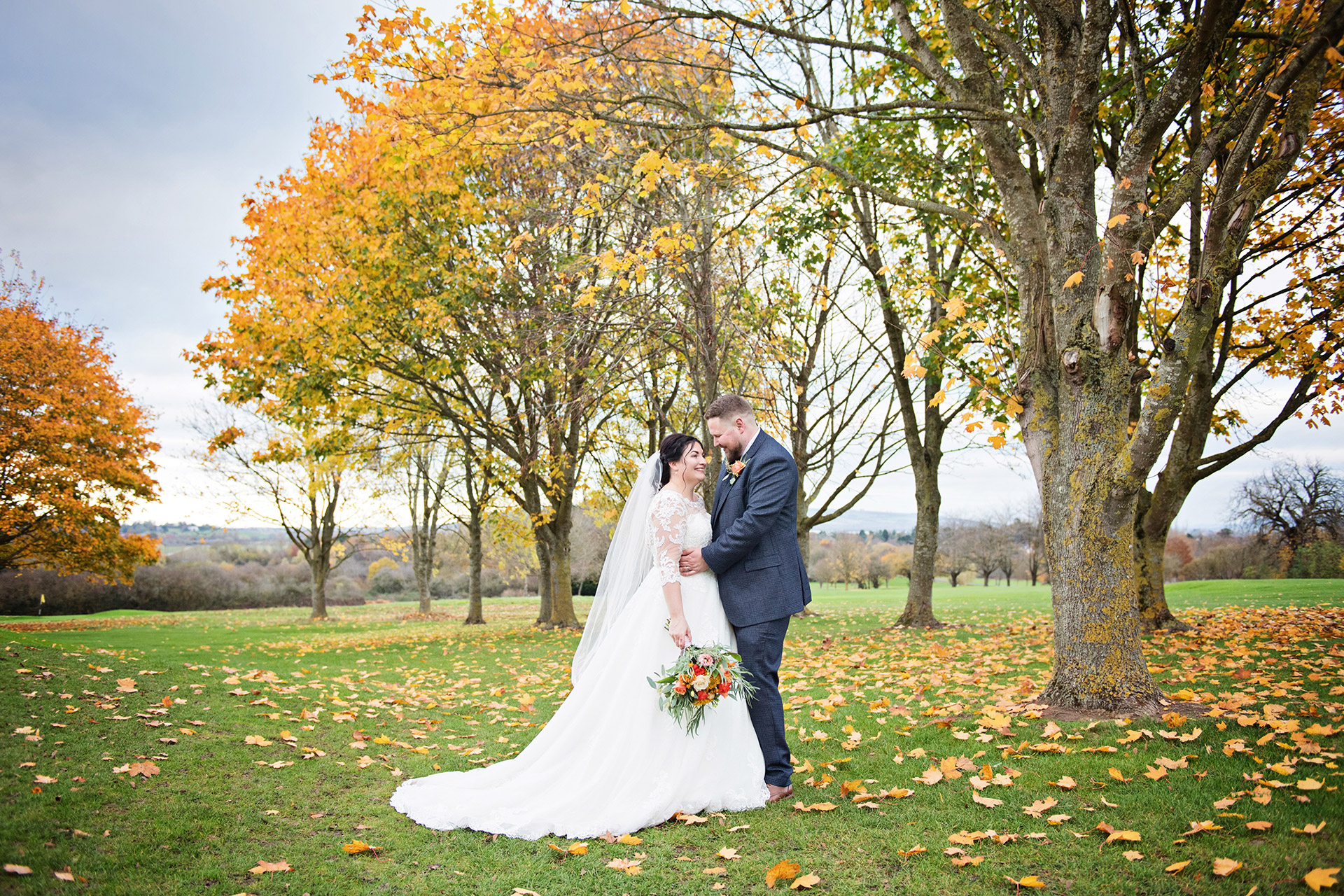 Bride and Groom take a break from their guests and relax with Autumnal colour behind them. Taken at Tewkesbury Park Hotel