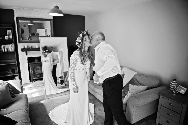 Father of the Bride kisses his daughter aka bride, as he see's her for the first time. B&W photo by Blooming Photography