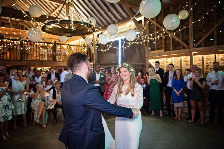Bride and groom dance, surrounded by their friends and family in a rustic barn called Over Barn, Gloucester. Candid photo by Blooming Photography