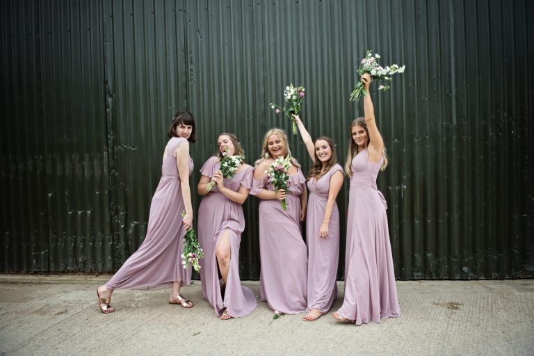 Bridesmaids pose in front of metal barn. Looks fun. It was.