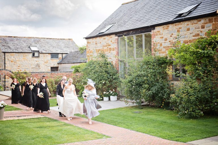 Bridal party and bride walk down a garden path on their way to the wedding at Blackwell Grange.