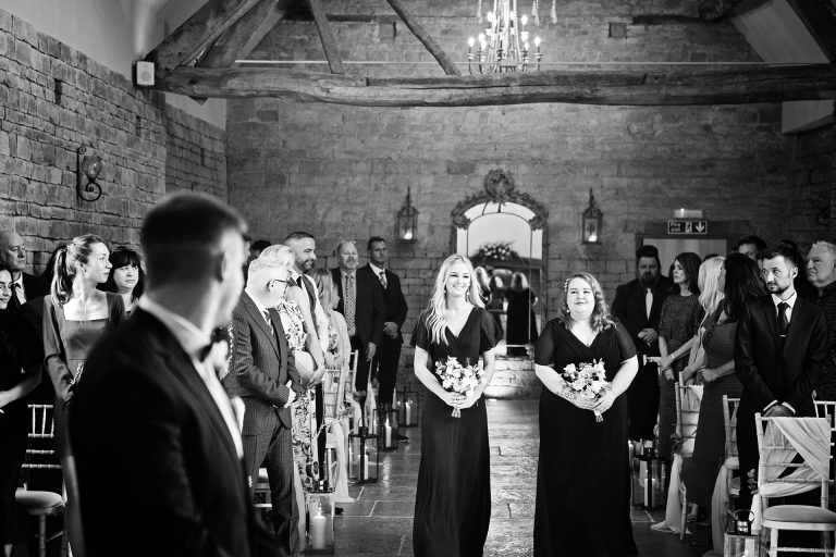 B&w image of bridesmaids walking down the wedding isle at Blackwell Grange.