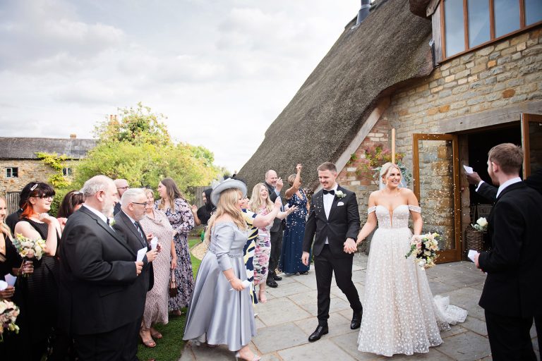 Bride and groom getting showered by their guests in confetti. Candid photo by Blooming Photography taken at Blackwell Grange.