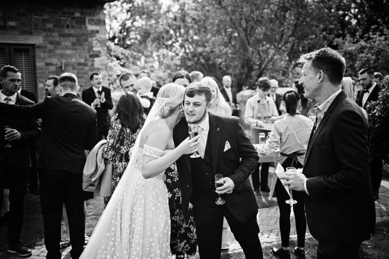 Candid photo by Blooming Photography taken at Blackwell Grange. B&w image of a bride being hugged by a wedding guest.