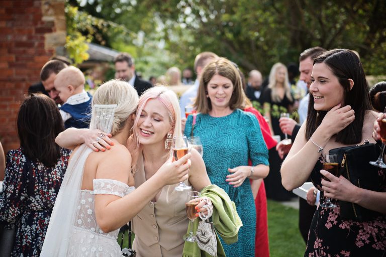 Candid photo by Blooming Photography taken at Blackwell Grange. A bride being hugged by a wedding guest