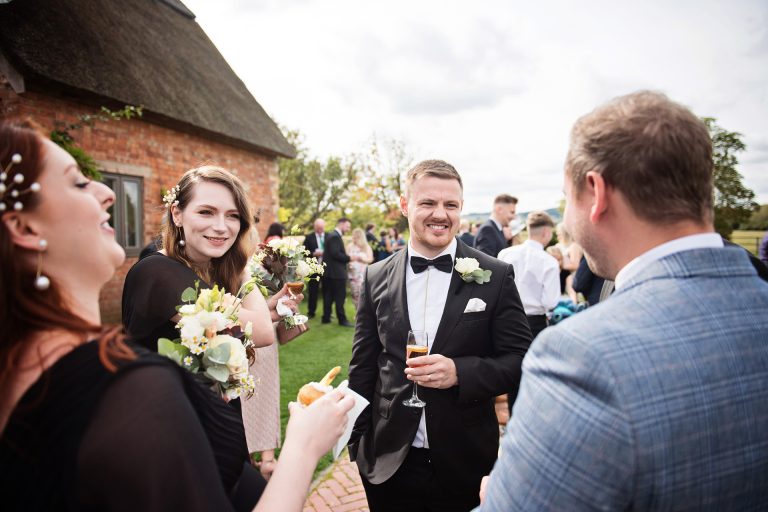 Candid photo by Blooming Photography taken at Blackwell Grange. A groom surrounded by his friends smiling and chatting