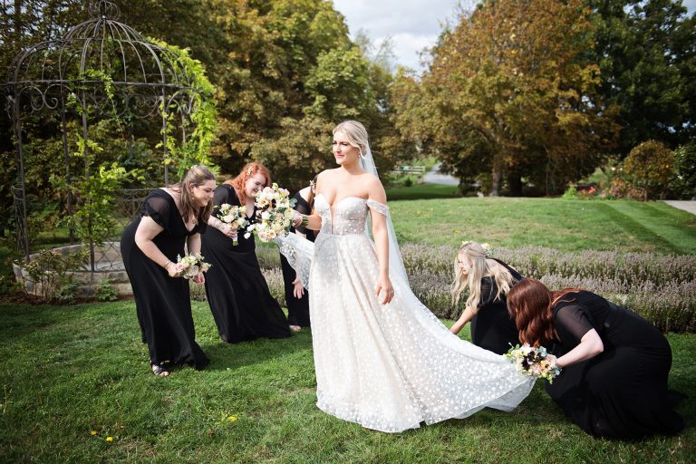 Elegant photo of the bridesmaids laying out the the brides wedding dress trail. Photo by Blooming Photography taken at Blackwell Grange, Warwickshire wedding.