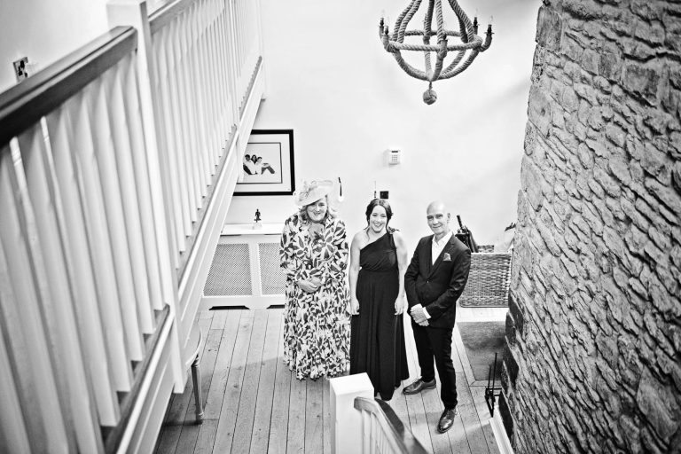 Storytelling photo of parents and sister waiting for the bride to walk down the stairs. Cardiff wedding photographer.