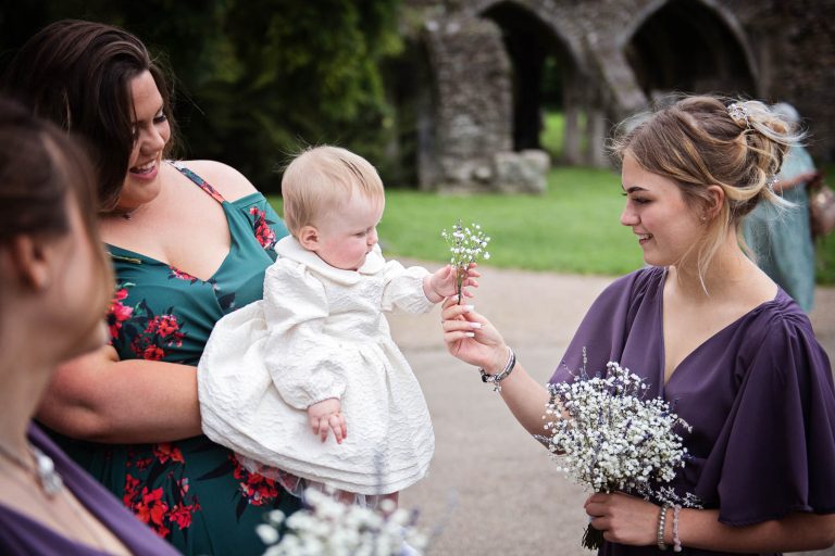 Natural wedding photo of flower girl and bridesmaid playing with the wedding flowers.