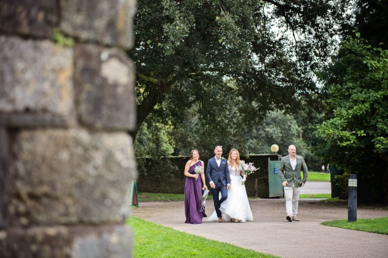 Bride walking with her father and bridesmaid as they arrive at Margam Country Park.