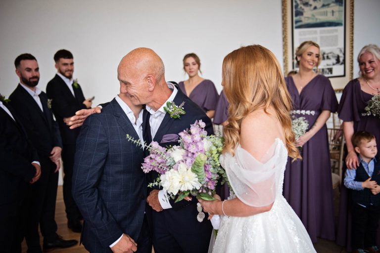 Photo of a father of the bride hugging the groom at a wedding ceremony at Welsh wedding venue.