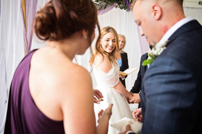 Photo of a bride and groom exchanging rings at a wedding.