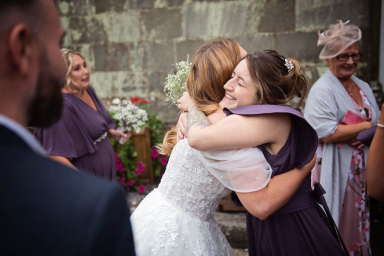 Relaxed moments of guests hugging a bride.
