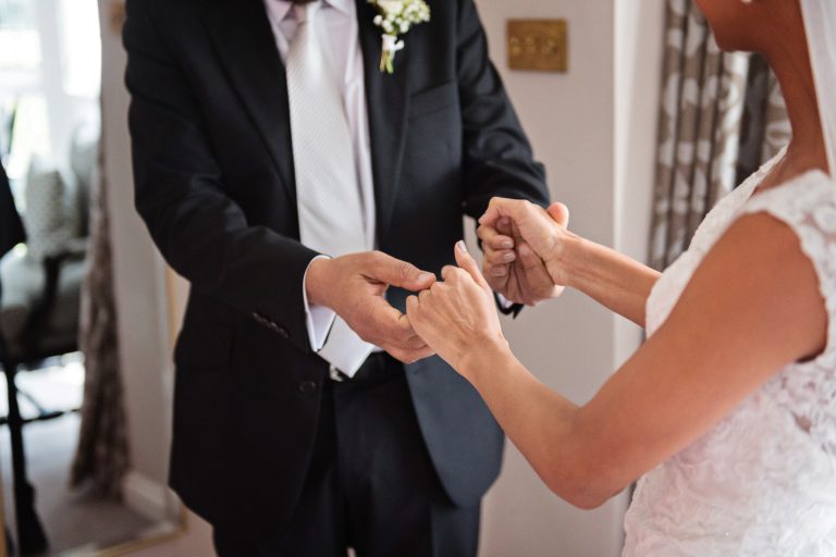 Father of the bride holds his daughters hands.
