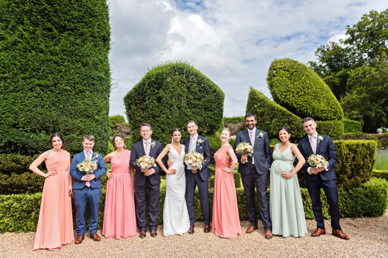Fun group shot of the bridal party. Groomsmen hold the bridesmaids flowers. Fun and relaxed. Photographed at Danesfield House Hotel and Spa.