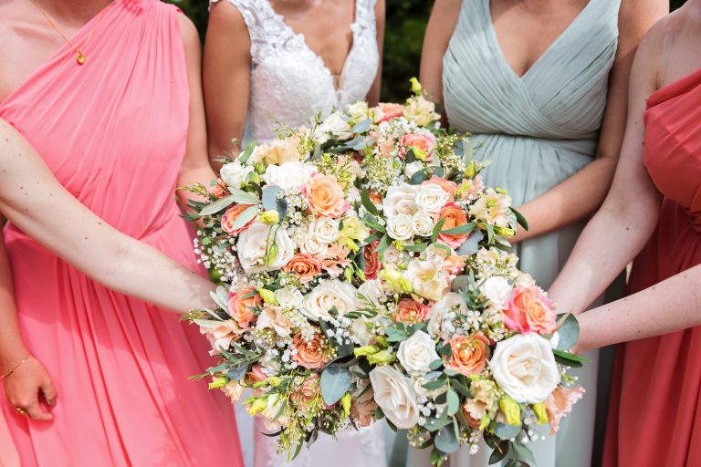 Bride and bridesmaids hold out their wedding bouquets into one big bunch. Photographed at Danesfield House Hotel and Spa.
