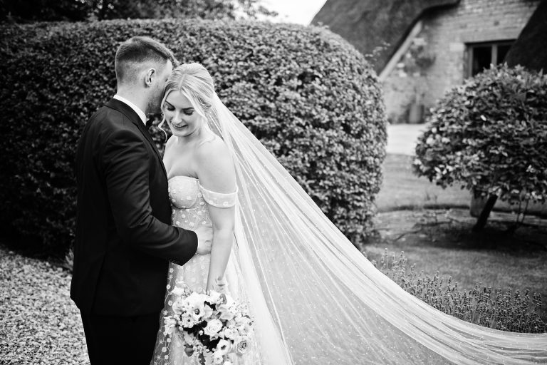 B & W image of a bride and groom spending time together. The veil is laid out across the picture. Stunning photo by Blooming Photography taken at Blackwell Grange, Warwickshire wedding.