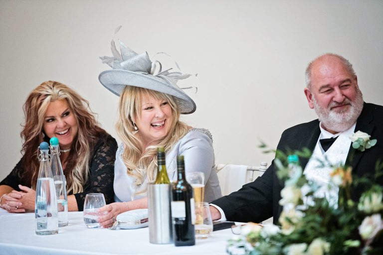 Mother of the bride laughing during the wedding speech. Candid photo by Blooming Photography. Taken at Blackwell Grange, Warwickshire.