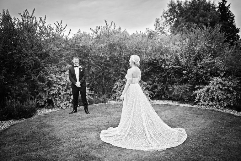 B&w classic image of bride and groom looking at each other from afar. Candid photo by Blooming Photography. Taken at Blackwell Grange, Warwickshire.