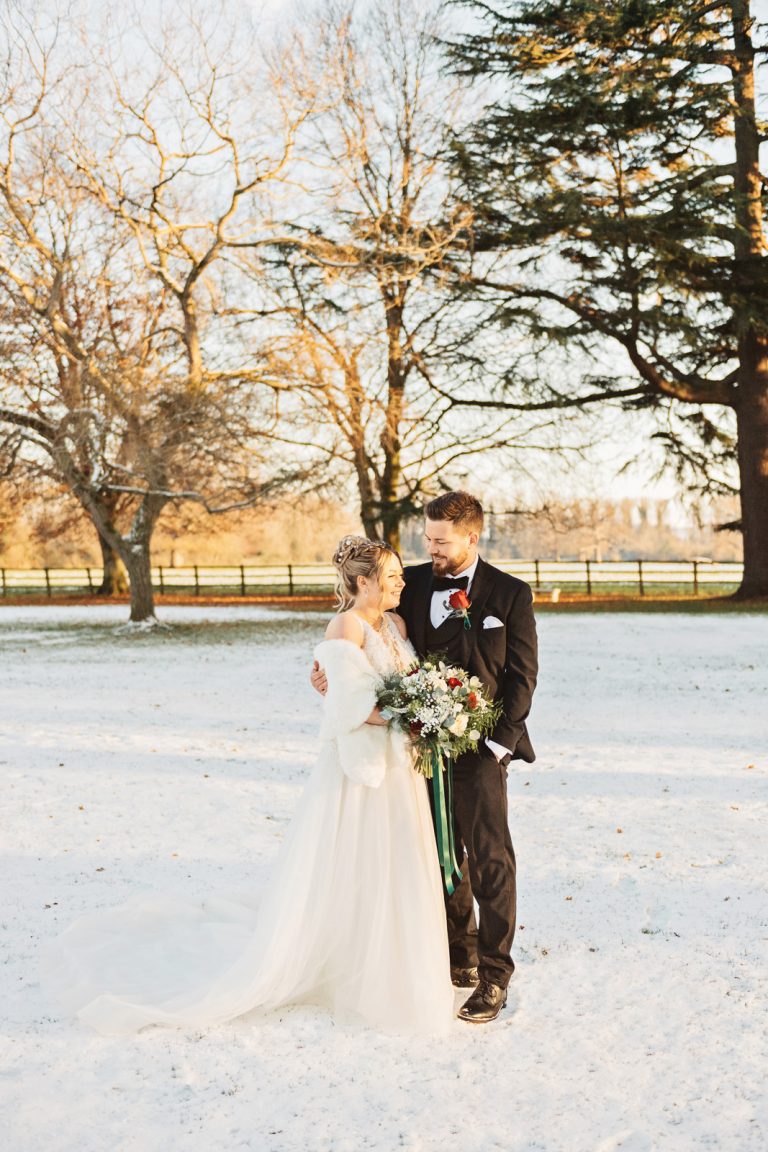 Bride and groom chat closely with the snowy grounds at Eastington Park.