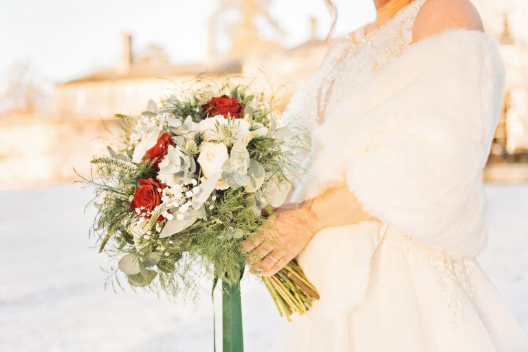 A close up photo bride holding her wedding bouquet with snow and Eastington Park behind them.