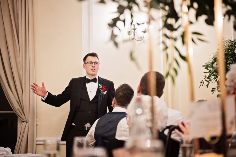 Best man delivers his wedding speech in front of the wedding guests. Photograph by Blooming Photography taken at Eastington Park at Christmas Wedding.