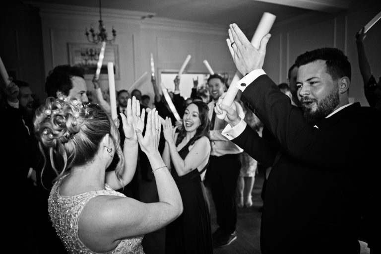 Bride and groom clapping with their guests at the end of the first dance, black and white photo. Taken at Eastington Park at Christmas Wedding.