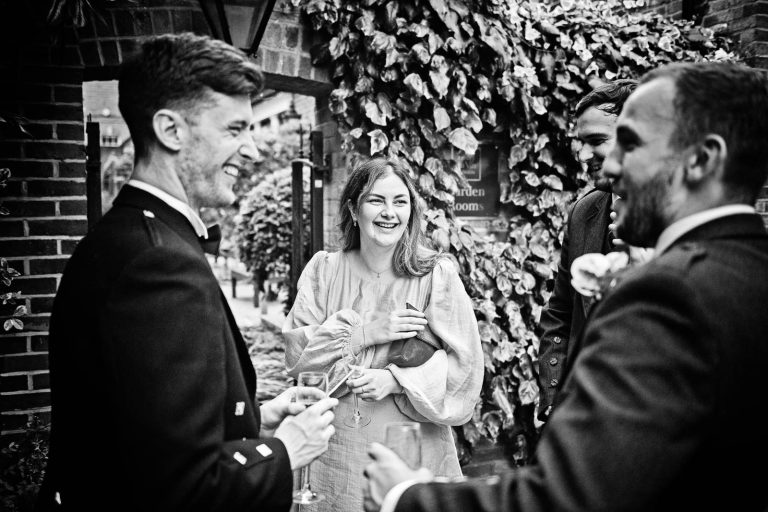 Storytelling wedding photo of guests talking to bride at Hotel Du Vin Winchester, Black & white photo by Blooming Photography