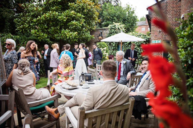 Relaxed wedding photo of guests talking in the gardens at Hotel Du Vin Winchester, photo by Blooming Photography