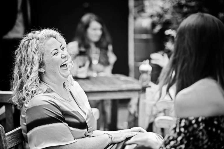 Candid wedding photo of guests laughing at Hotel Du Vin Winchester, Black & white photo by Blooming Photography