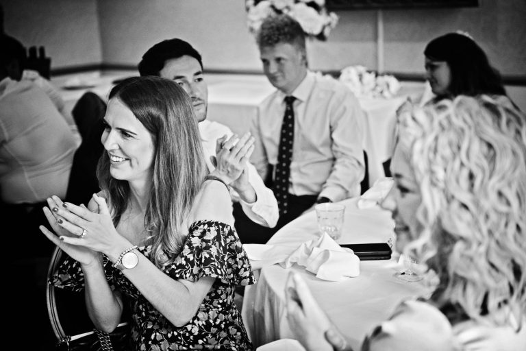 Candid black and white photograph of a guest clapping after the end of speeches taken at Hotel du Vin, Winchester by Blooming Photography