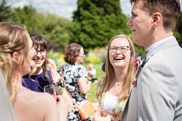 Documentary style wedding photography of guests chatting and laughing with the bride.