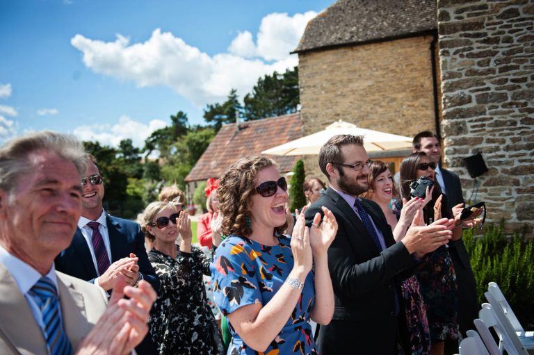 Outdoor wedding ceremony with happy people clapping taken by Blooming Photography