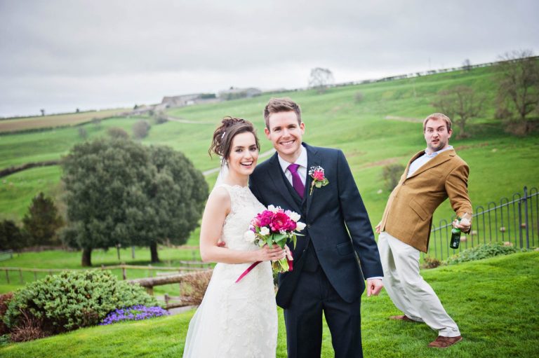 Funny wedding photo of bride and groom with a guest doing a photo bomb at Kingscote Barn