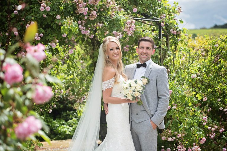 Bride and groom in the rose garden at Kingscote Barn