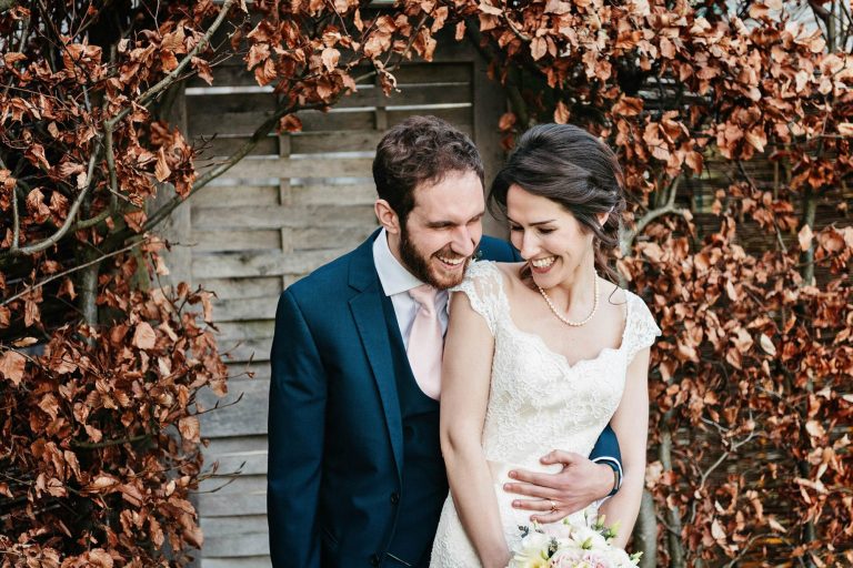 Natural wedding photograph of bride and groom laughing taken at Kingscote Barn